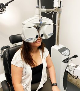 A patient sitting behind some eye examination equipment during a comprehensive eye exam.