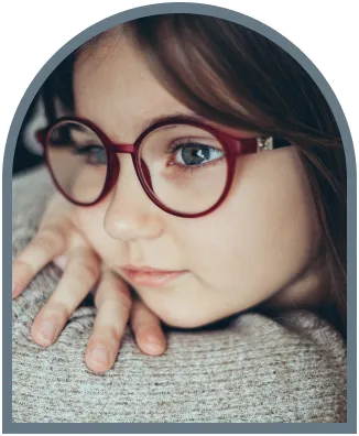 Child wearing glasses resting chin on hand close-up portrait